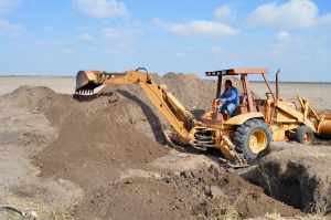 A back hoe filling in a pit.