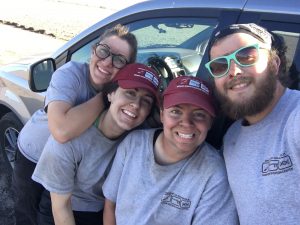 Smiling team members covered in dirt after a day of work.