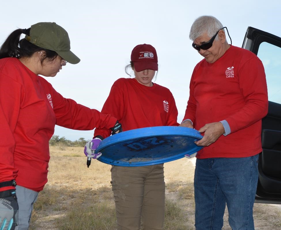 Team members with Eddie Canales of the South Texas Human Rights Center writing on the lid of a water station
