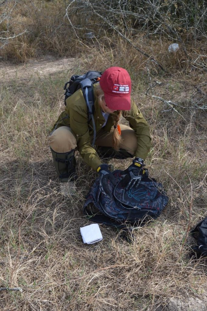 Team member searching through a discarded backpack