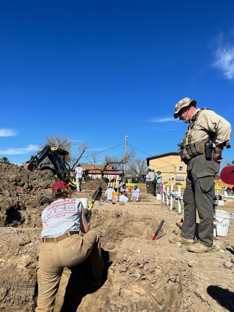 Deputy White watching Olivia work on the trench