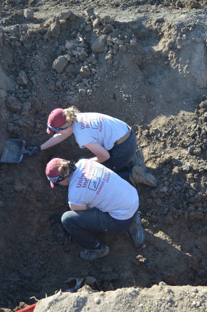 Two team members removing dirt from a burial