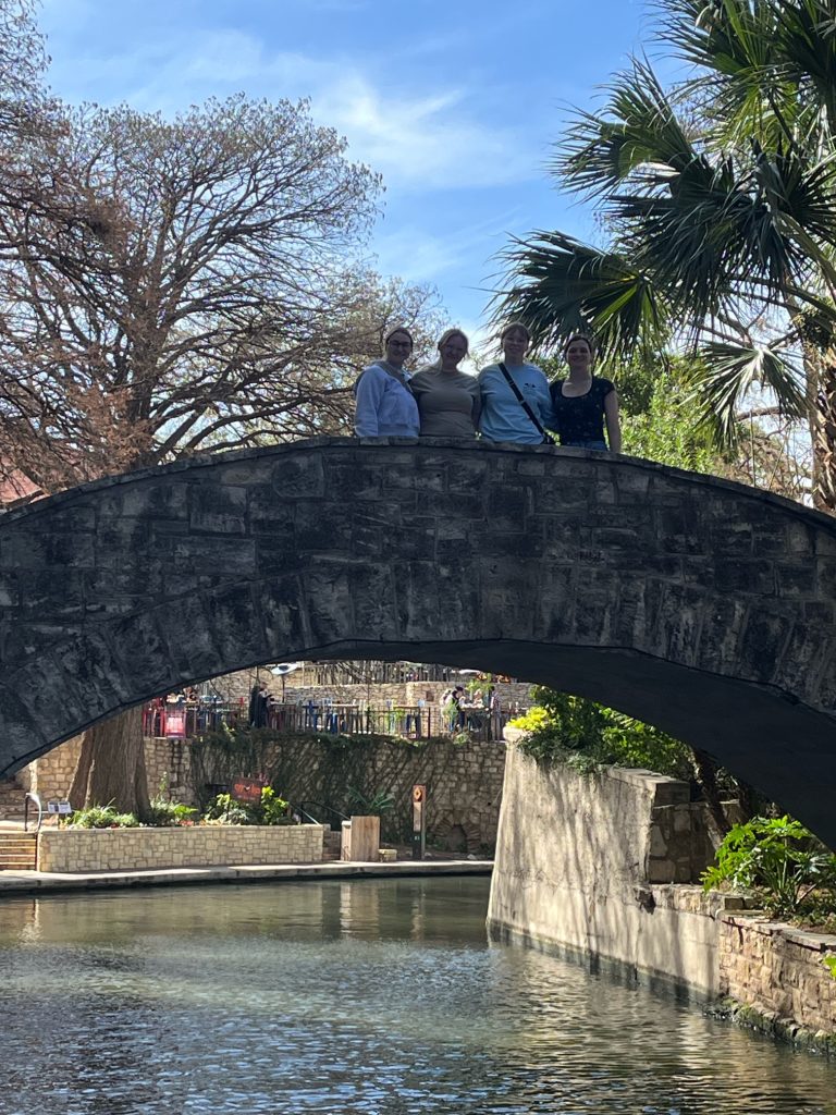 part of the team standing on top of a bridge on the Riverwalk