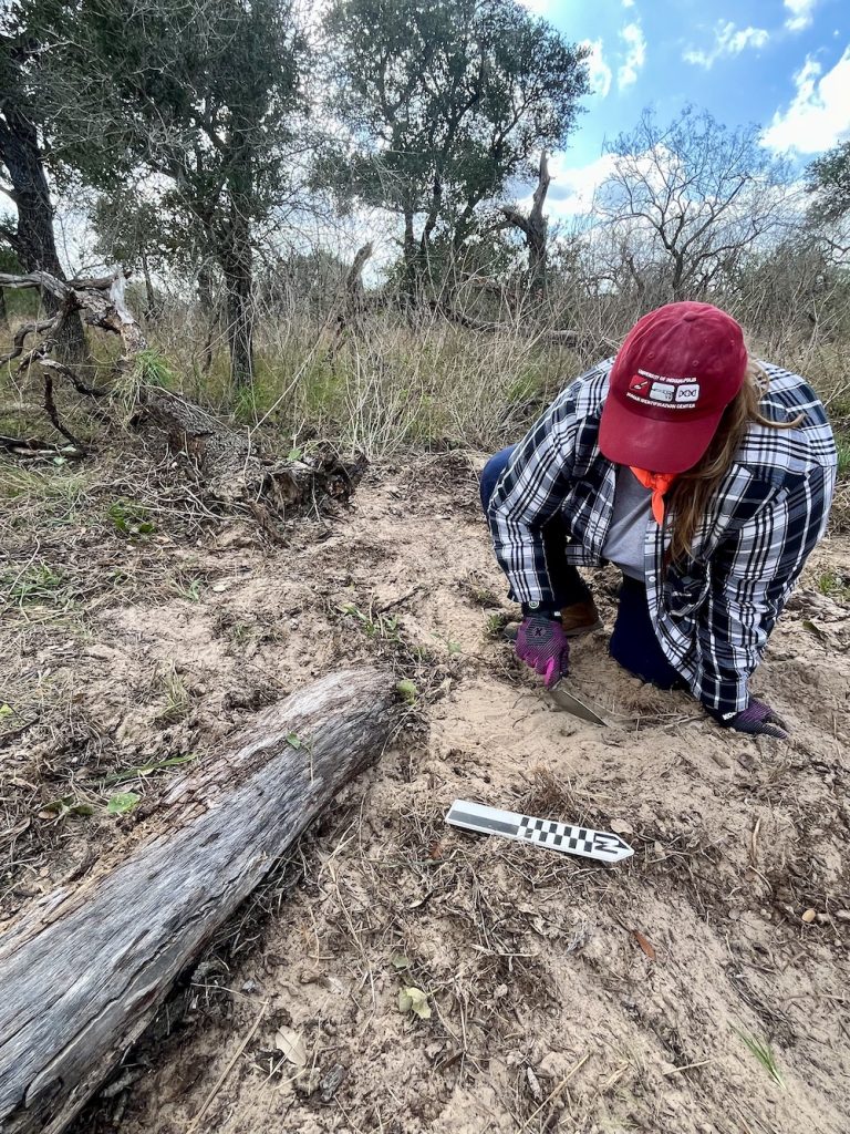 Amandine Eriksen using trowel to remove top layer of dirt.