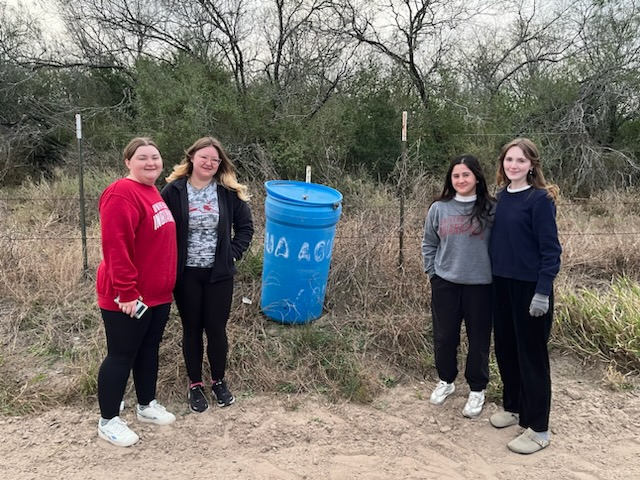 Beyond Borders Team members posing in front of a water station