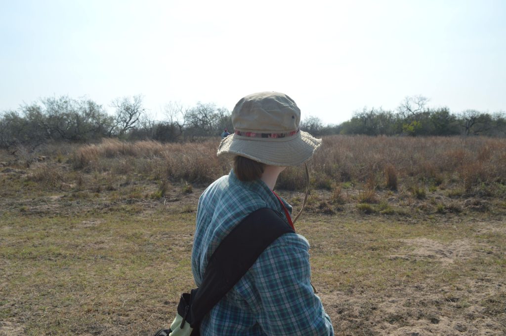 Taken from behind, Peytin stands looking out at the vast ranchland