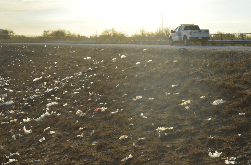 Trash littering the hill with the wall in the background.